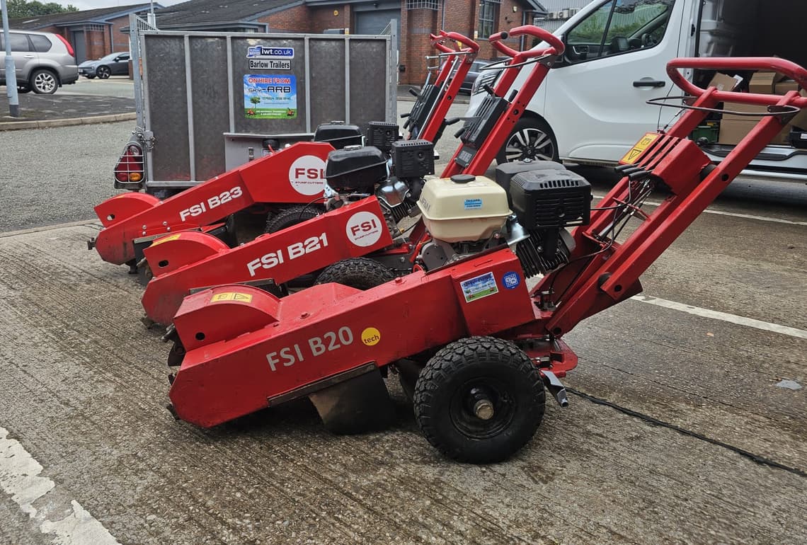 The three FSI stump grinders lined up outside the workshop, with the trailer they go out on.